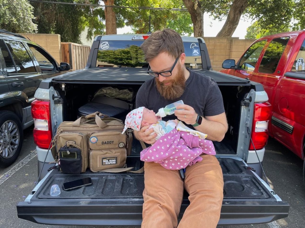 Reid holds his daughter, Kaylee Nari, on the bed of his pickup truck.